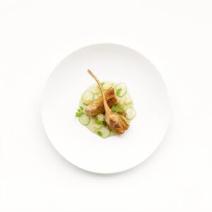 Geflämmte Artischockenviertel auf heller Kombu-Crème mit grüner Erdbeere und Yuzu-Granité, präzise zentriert auf weißem Teller.