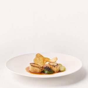 Geflämmter Topinambur mit Kaviar, grüner Erdbeere und Shiso-Crème auf weißem Teller