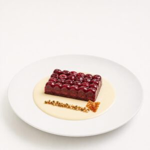 Glasiertes Kirschmosaik auf kalter Mandel-Vanille-Crème mit feinem Kapernkrokant auf einem weißen Teller