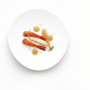Rote Garnele mit Yuzu, fermentiertem Fenchel und Krustentierblatt auf einem weißen Teller