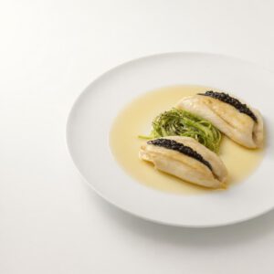 Präzise angerichtete Seezunge mit heller Rauchmolke, schwarzem Knoblauch und Puntarelle auf einem weißen Teller