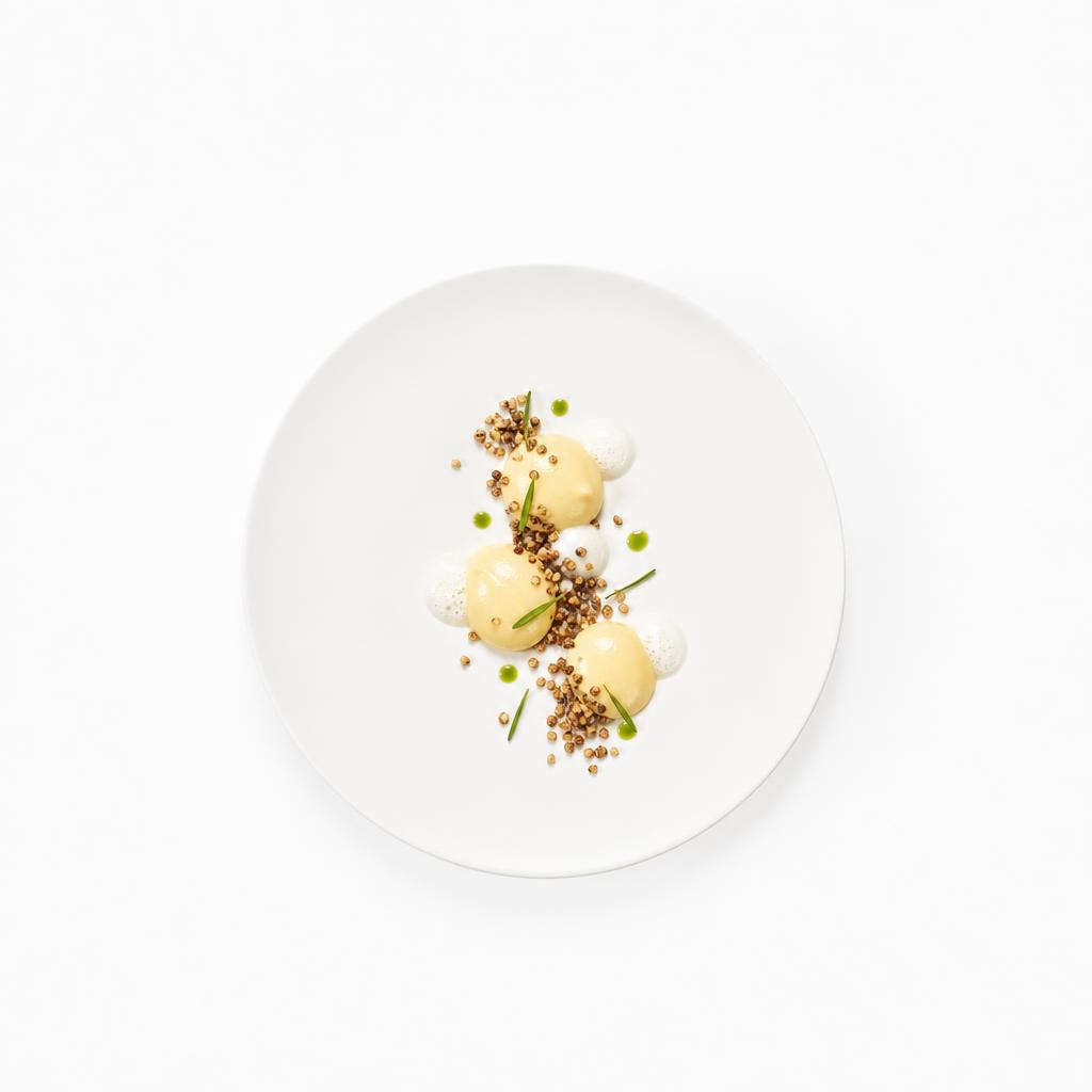 Yuzu-Crémeux mit Buchweizenstreusel, feiner Yuzu-Beurre-blanc und Estragonöl auf einem weißen Teller